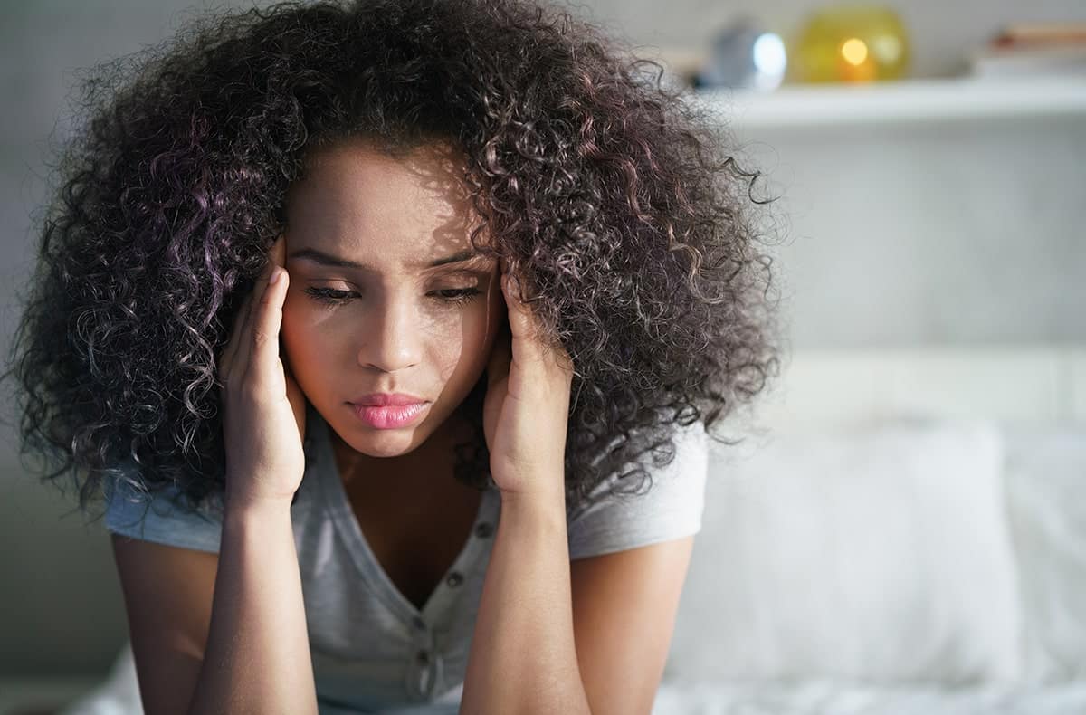 Anxiety can be debilitating-min woman massaging the sides of her head, a symptom of sleep apnea